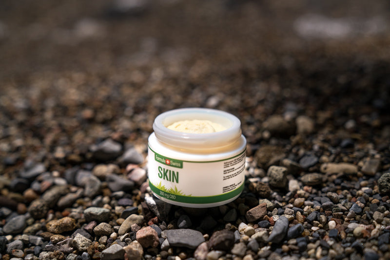 Odprt lonček balzama Formula Swiss CBD Skin, 300 mg CBD, na prodnati plaži