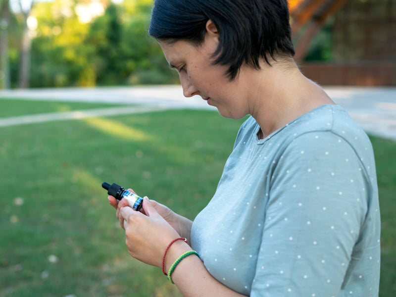 Ženska na prostem gleda stekleničko CBD olja Formula Swiss v roki